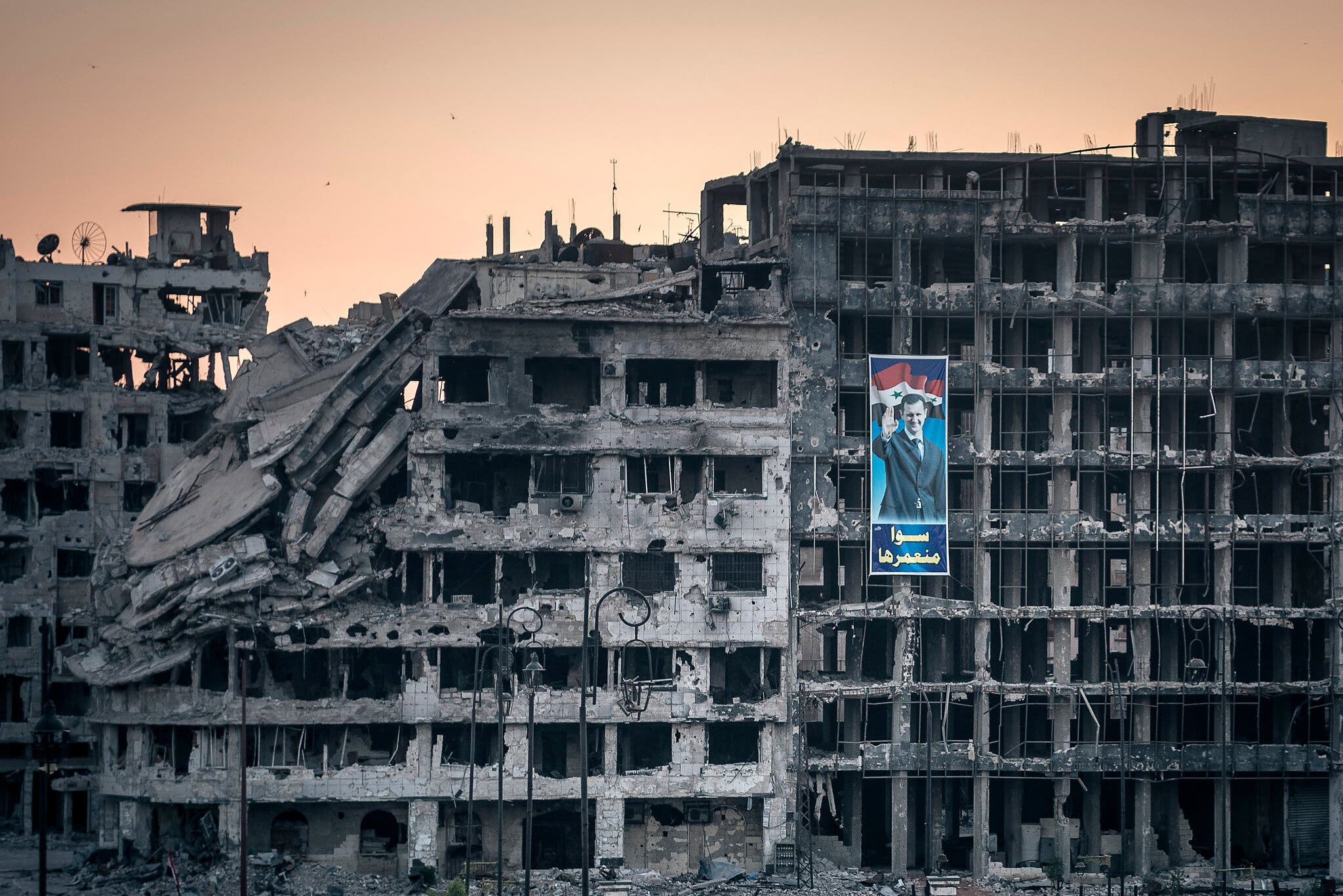 ملصق للرئيس بشار الأسد في مركز تجاري مدمر في حمص، سوريا سنة 2014.